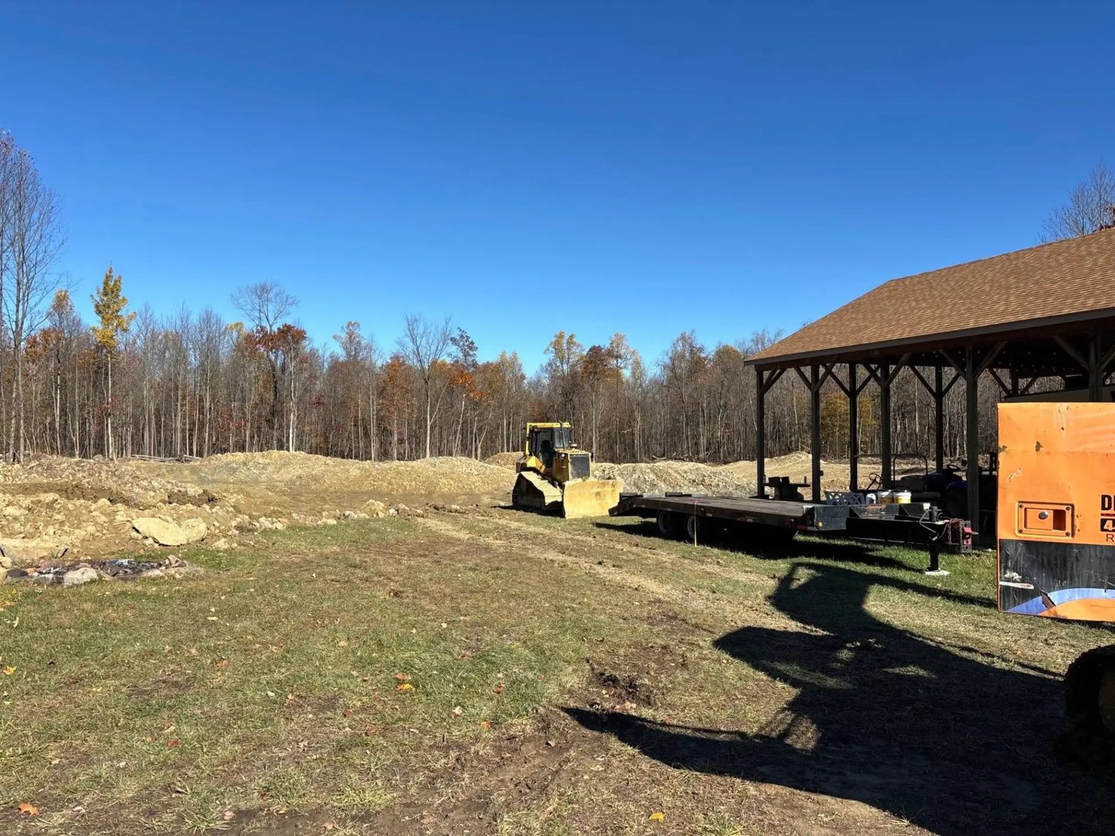 Bulldozer on freshly cleared land beside a pole barn
