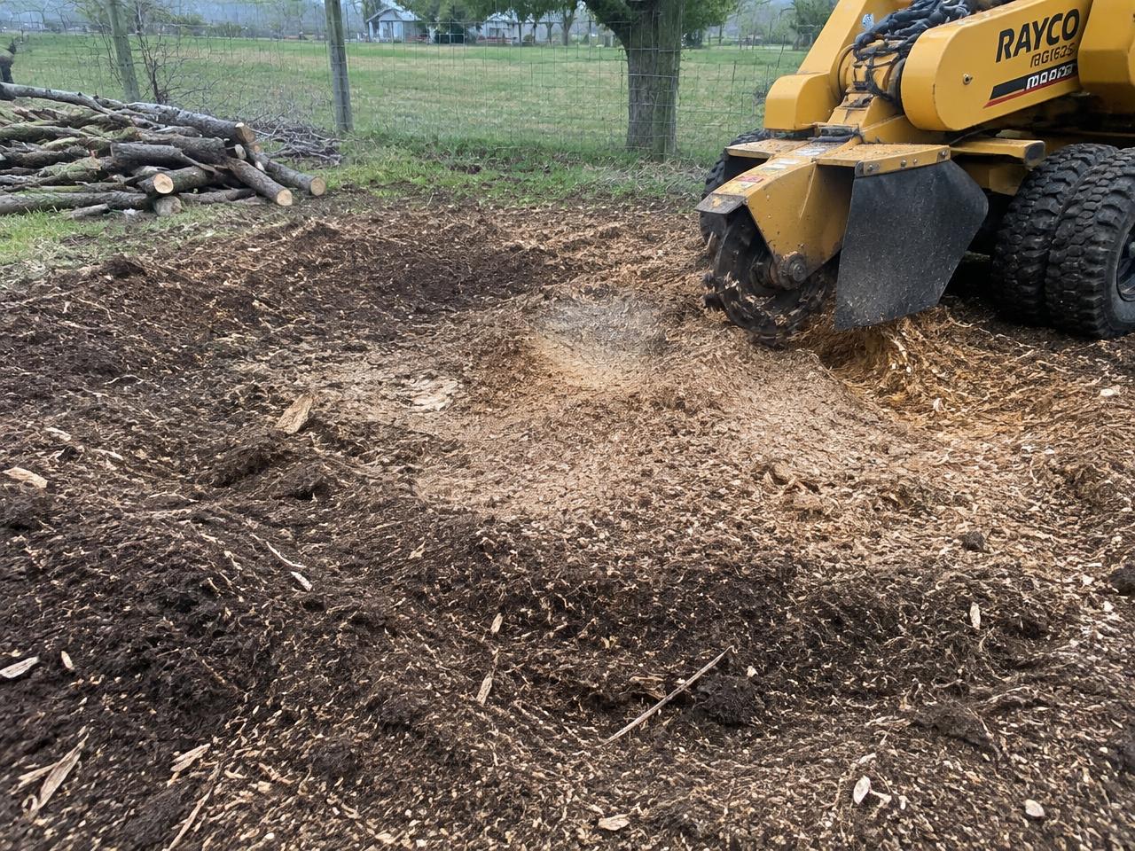 Ground stump area with wood chips beside a stump grinder
