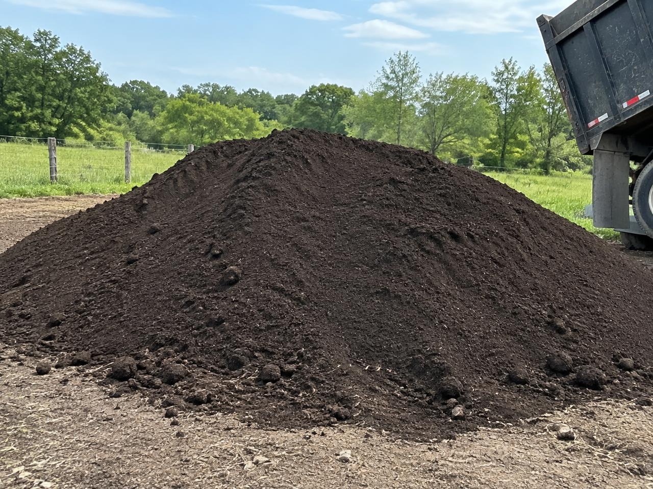 Large pile of dark topsoil on a rural property